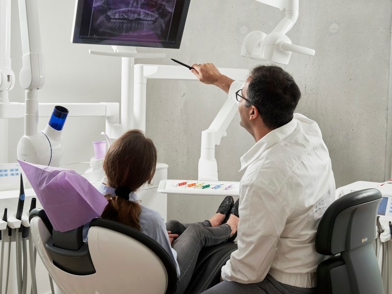 A dentist talking with a patient in the treatment chair