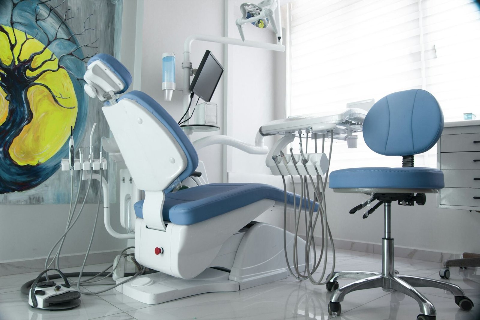 An empty dental treatment room with a blue chair