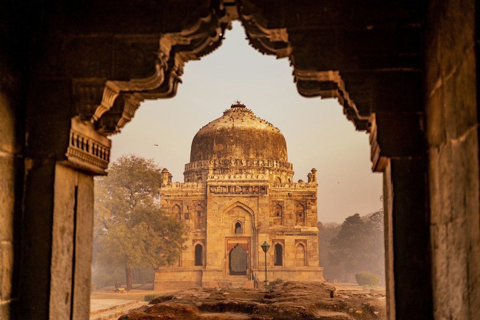 Shisha Gumbad framed by a stone arch at Lodhi Garden, New Delhi, in early morning light