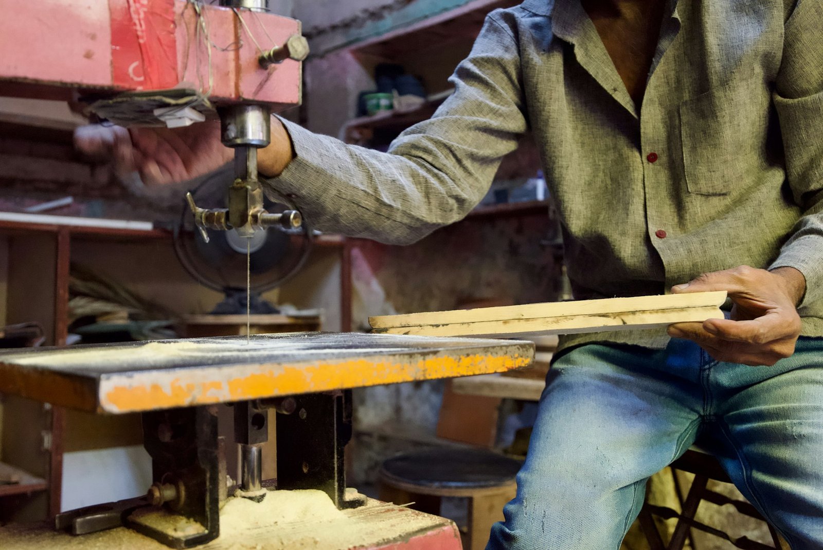 A carpenter cutting wood with a saw in a workshop