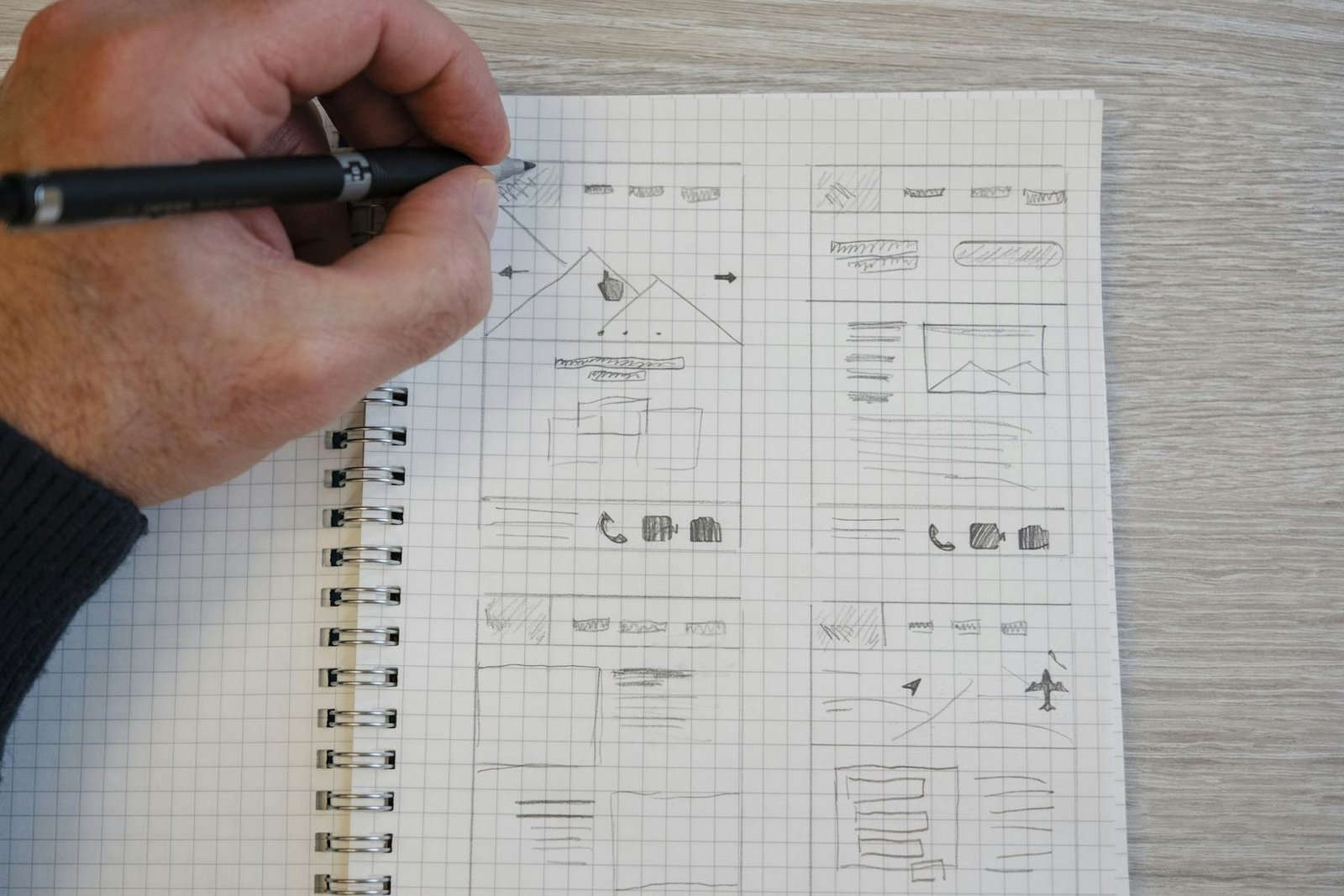 A hand sketching website wireframes in a notebook